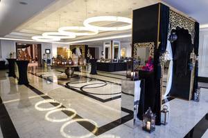 Foyer des Taj Dubai Hotels mit schwarzen und weißen Marmorboden, schwarzen Vorhängen und goldenen Kronleuchtern.