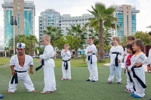 Kinder nehmen an einem Kung-Fu-Kurs im Freien vor dem Sherwood Exclusive Lara Hotel teil.