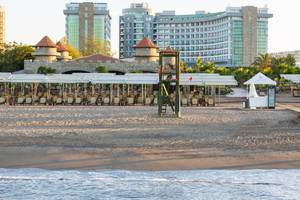 Strand des Sherwood Exclusive Lara Hotels mit Gebäuden im Hintergrund.