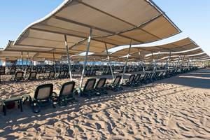 Reihen von Sonnenliegen unter Sonnenschirmen am Strand des Sherwood Exclusive Lara Hotels.