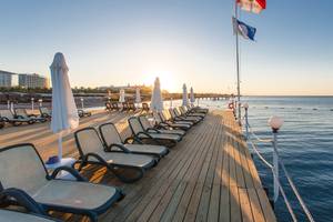 Hotelterrasse des Sherwood Exclusive Lara mit Sonnenliegen und Schirmen am Meer