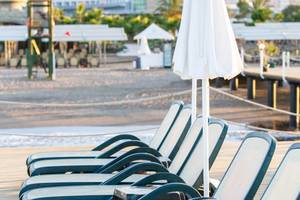 Reihe von Liegestühlen mit Sonnenschirmen auf der Terrasse des Sherwood Exclusive Lara Hotels.