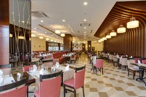 Innenansicht des Restaurants im Sherwood Exclusive Lara Hotel mit gemustertem Boden und elegant eingerichteten Tischen.