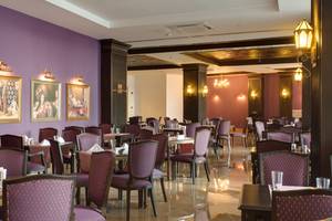 Sherwood Exclusive Lara Hotel Restaurant mit lila Wänden, gepolsterten Stühlen und gedeckten Tischen.