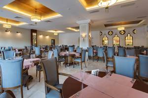 Innenbereich des Restaurants im Sherwood Exclusive Lara Hotel mit blauen Stühlen und Tischen, dekorativ beleuchteten Decken und Wänden.