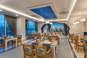 Innenansicht des Restaurants des Sherwood Exclusive Lara Hotels mit blauer Decke und großen Fenstern.