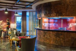 Innenansicht des Restaurants des Sherwood Exclusive Lara Hotels mit einer Theke und rauchenden Personen.