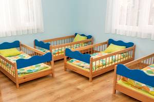 Ein Zimmer mit mehreren blauen Kinderbetten auf hölzerne Böden, jeden mit gelben Kissen