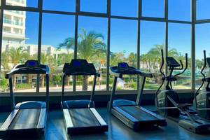 Fitnessstudio mit Laufband und Blick auf Palmen und Gebäude im Sherwood Exclusive Lara