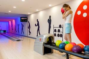 Frau im Sherwood Exclusive Lara Hotel in der Bowlinghalle, die eine Bowlingkugel hält.