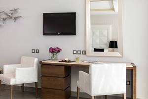 Büroschreibtisch im Boutique 5 Hotel & Spa Zimmer mit Fernseher, Spiegel, Blumen und Stühlen.