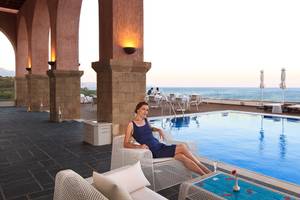 Eine Frau sitzt auf einer weißen Liege neben einem Pool im Boutique 5 Hotel & Spa.