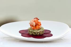 Gegrillter Garnelen-Risotto auf einem weißen Teller mit Rote-Bete-Scheibe.