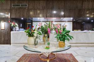 Empfangsbereich des Creta Star Hotels mit runden Tisch und Blumenarrangements.