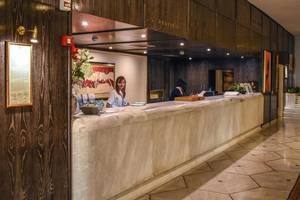 Empfangsbereich des Creta Star Hotels mit einer Rezeptionistin, die einen Gast bedient.