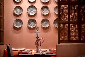 Tisch im Westin Resort Costa Navarino mit einer Narghile und dekorativen Tellern an der Wand.
