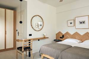 Schlafzimmer mit Doppelbett, Spiegel und Holzmöbeln im Domes of Elounda, Autograph Collection.