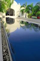 Ein großer Swimmingpool neben dem Swahili Beach Resort mit spiegelndem Wasser und umgebenden Pflanzen.