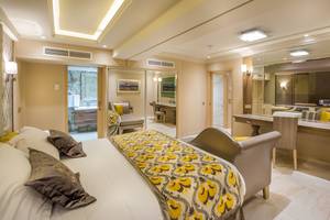 Innenansicht eines Schlafzimmers im Adams Beach Hotel mit Bett, Schreibtisch und Spiegeln.