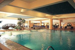 Ein großer Pool im Adams Beach Hotel mit einer Brücke und Liegestühlen