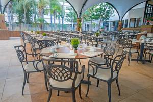 Innenbereich eines Restaurants im Adams Beach Hotel mit vielen runden Tischen und Stühlen.