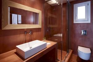 Ein Badezimmer im Vencia Boutique Hotel mit einem Waschbecken, einer Glasdusche und einem Toilettensitz.