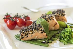 Portion Lachs auf einem Teller mit Gemüse und Kirschtomaten