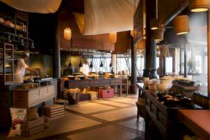 Innenansicht des Restaurants im LUX South Ari Atoll Hotel mit Köchen, die Speisen zubereiten, und vielen Gerichten, die serviert werden.