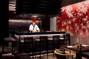 Restaurantbar im LUX South Ari Atoll mit rotem Hintergrund und einem Koch in traditioneller Kleidung.