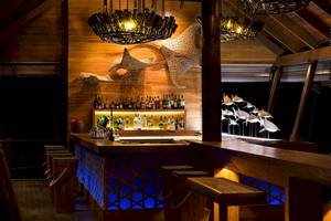 Bar im LUX South Ari Atoll Hotel mit Holztheke und blauer Beleuchtung.