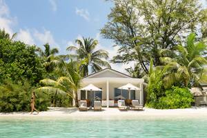 Villa am Strand des LUX South Ari Atoll Hotels mit Frau und Palmen