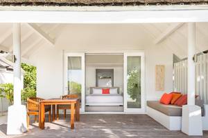 Außenbereich der Suite im LUX South Ari Atoll Hotel mit Tisch, Stühlen und offenem Schlafzimmer.