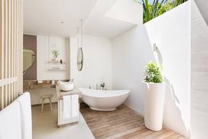 Modernes Badezimmer im LUX South Ari Atoll Hotel mit Badewanne, zwei Waschbecken und Holzboden.