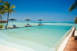 Pool-Lounge-Bereich im LUX South Ari Atoll Hotel mit Sonnenschirmen und Liegen