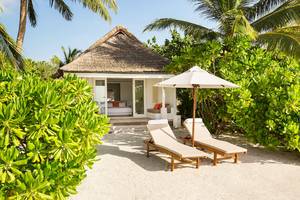 Strandhaus des LUX South Ari Atoll mit Sonnenliegen und einem Schirm