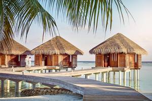 Drei traditionelle Hütten am Wasser im LUX South Ari Atoll Hotel.