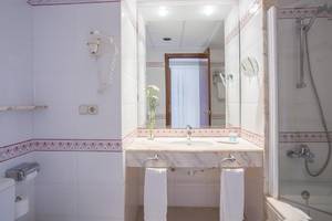 Badezimmer im Hipotels Said Hotel mit weißem Waschbecken, Spiegel und Handtüchern.