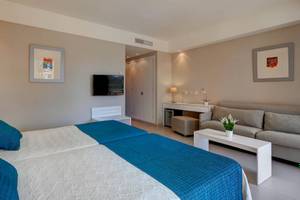 Innenansicht eines Doppelzimmers im Hipotels Said Hotel mit zwei Betten, einem Fernseher und einer Couch.