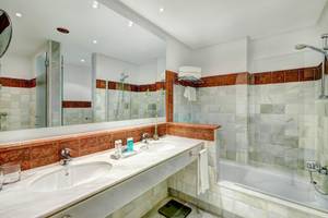 Badezimmer des Hipotels Said mit zwei Waschbecken, Badewanne und Dusche.