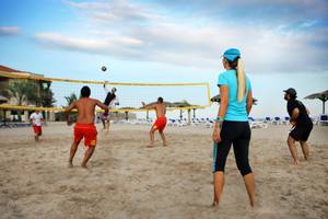 Gruppe von Menschen spielt Volleyball am Strand vor dem Fujairah Rotana Resort & Spa.