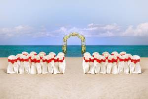 Hochzeitszeremonie am Strand des Fujairah Rotana Resorts & Spa mit blumengeschmücktem Tor.