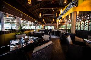 Innenansicht des Restaurants im Fujairah Rotana Resort & Spa mit runden Tischen und Stühlen.