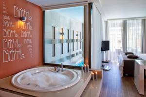Das Badezimmer der Avra Imperial Hotel Suite mit einem Whirlpool und einem Bett.
