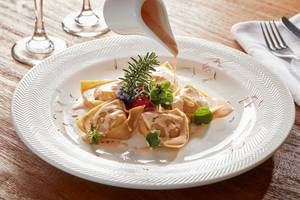 Ein Teller mit gefüllten Ravioli auf dem Avra Imperial Hotel serviert wird.