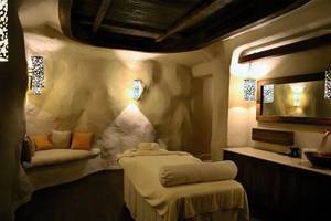 Behandlungsraum im Hotel Spa des Pickalbatros The Palace Port Ghalib mit Massageliege, Kissen, Wandleuchten und Spiegel.
