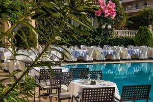 Pool-Essbereich des Hersonissos Palace Hotels mit gedeckten Tischen und Stühlen.