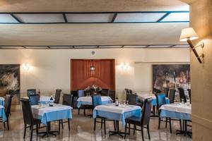 Innenansicht des Restaurants im Hersonissos Palace Hotel mit blauen Tischdecken und dunklen Stühlen.