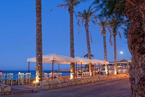 Strandbar des Hersonissos Palace Hotels bei Abend mit Palmen und Meer im Hintergrund.