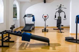 Fitnessraum im Hersonissos Palace Hotel mit Laufband, Hantelbank und anderen Geräten.