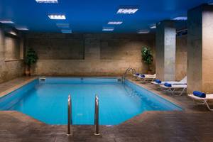 Innenpool im Hersonissos Palace Hotel mit blauen Kacheln und Lounge-Sesseln.